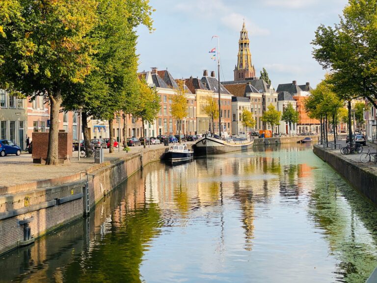 boat on river near trees and buildings during daytime