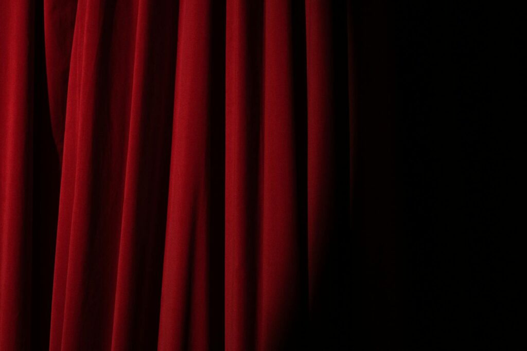 Elegant red velvet curtain with dramatic lighting perfect for theater themes.